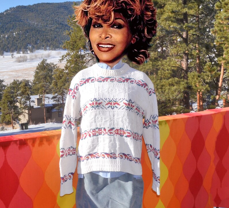 May include: White sweater with a red, blue, and white geometric pattern. The sweater has long sleeves and a crew neck.