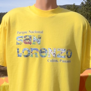May include: Yellow t-shirt with a colorful graphic of the words "Parque Nacional San Lorenzo" and "Colón, Panamá".