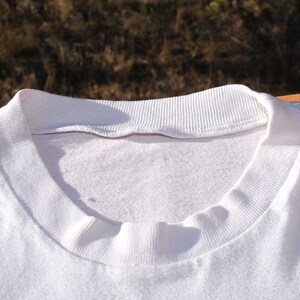 May include: White cotton t-shirt with a ribbed neckline.