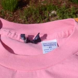 May include: Pink cotton t-shirt with a tag that reads "100% Cotton Women's -M- Made in U.S.A. Over 50"