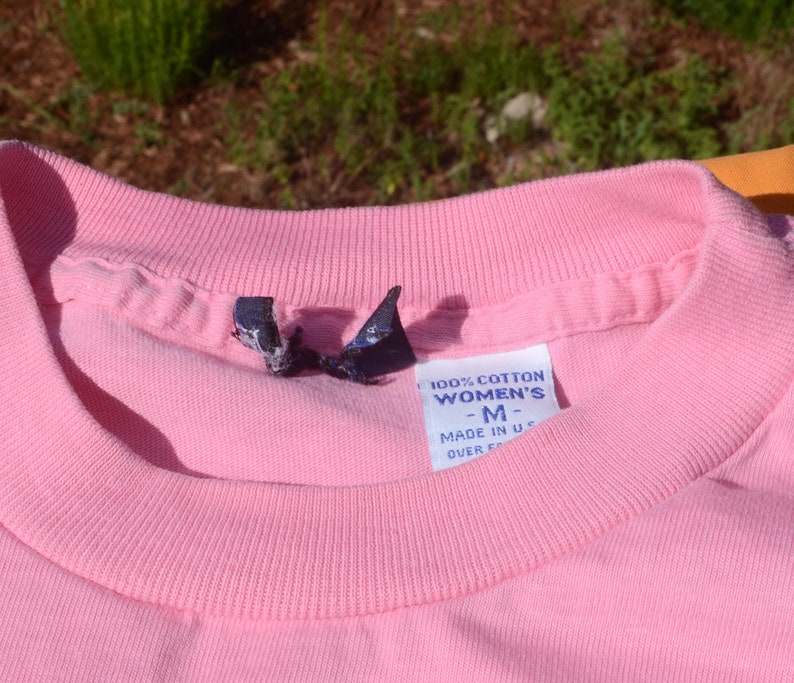 May include: Pink cotton t-shirt with a tag that reads "100% Cotton Women's -M- Made in U.S.A. Over 50"