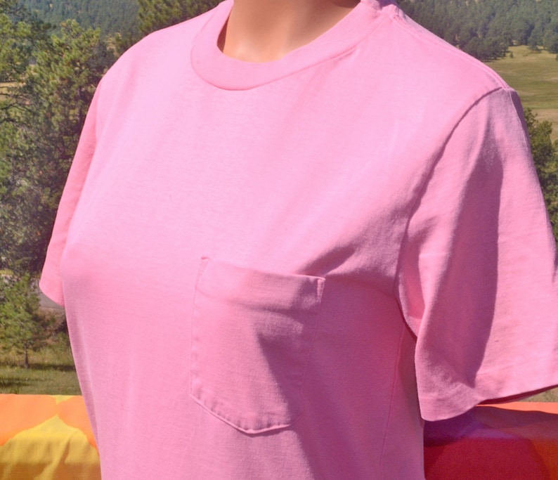 May include: A plain pink t-shirt with a single pocket on the left side.