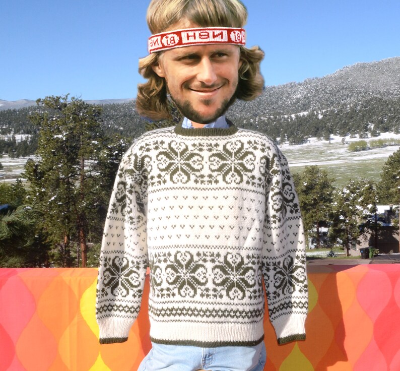 May include: White knitted sweater with a green snowflake pattern. The sweater has a crew neck and long sleeves.