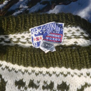 May include: Green and white knitted sweater with a label that reads "Ek & S&oslash;n" and "Gen. Strikket Norge".