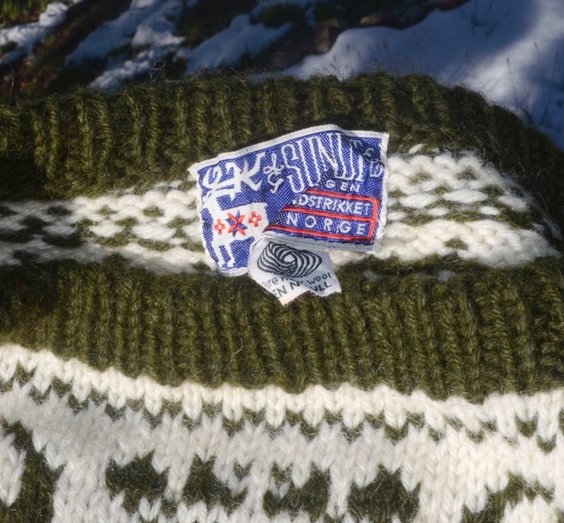May include: Green and white knitted sweater with a label that reads "Ek & S&oslash;n" and "Gen. Strikket Norge".