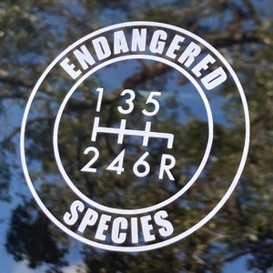 May include: White vinyl sticker with a black circle and white text that reads "ENDANGERED SPECIES" around a gear shift pattern with the numbers 1, 3, 5, 2, 4, 6, and R.