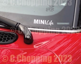 Può includere: Una Mini Cooper rossa con un adesivo bianco "MINI Life" sul parabrezza.