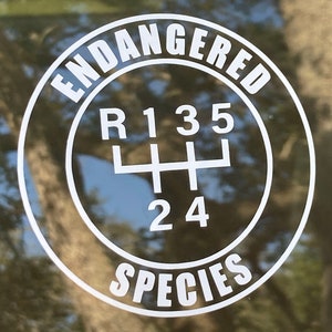 May include: White sticker with the words "Endangered Species" in a circle around a white gear shift pattern with the numbers 1, 2, 3, 4, and 5.