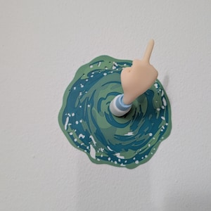 Peut inclure: Une décoration murale fantaisie représentant une main faisant un doigt d'honneur. La main est de couleur claire, avec une manche bleue et blanche émergeant d'un motif de portail tourbillonnant vert et bleu.