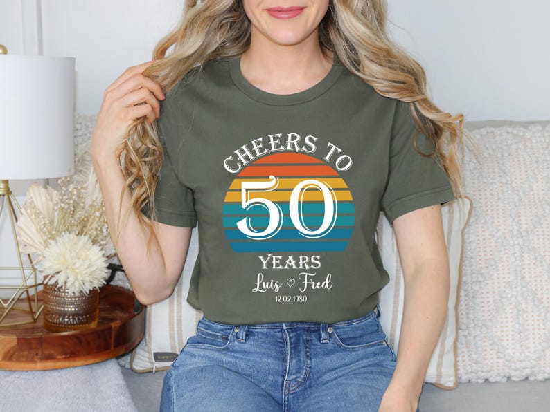May include: A green t-shirt with a sunset graphic and the text "Cheers to 50 Years Luis & Fred 12.02.1950".