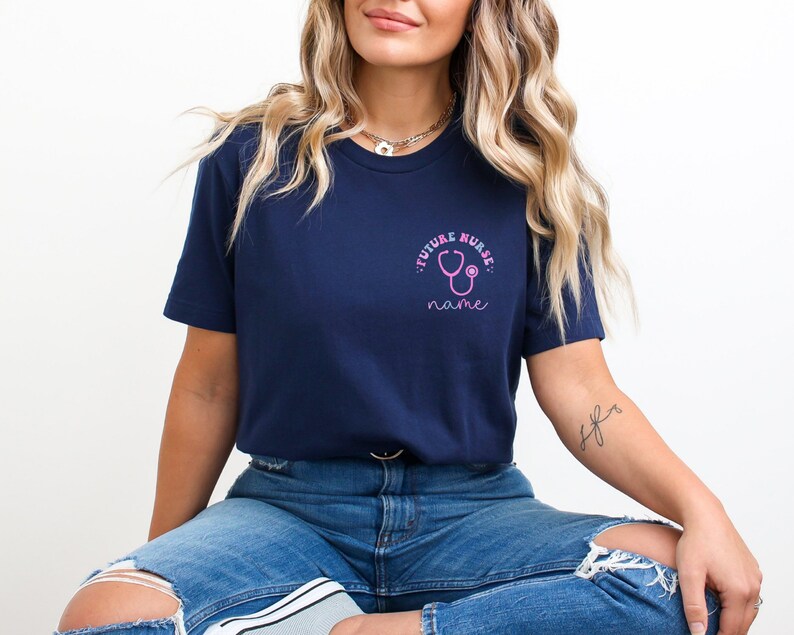 May include: Navy blue t-shirt with a pink stethoscope graphic and the words "FUTURE NURSE" and "name". The shirt is made of a soft material and is suitable for everyday wear. The design is on the upper left chest.