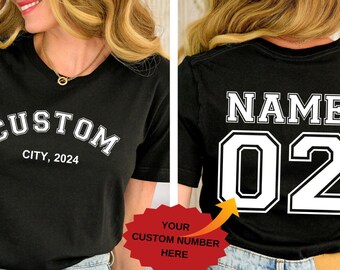 May include: Black t-shirt with white text. The front says "CUSTOM CITY, 2024". The back displays "NAME" above the number "02". A red sticker indicates where to add a custom number.