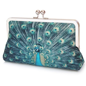 Bolso de mano con plumas de pavo real, bolso de tela con estampado azul verdoso y asa de cadena plateada.