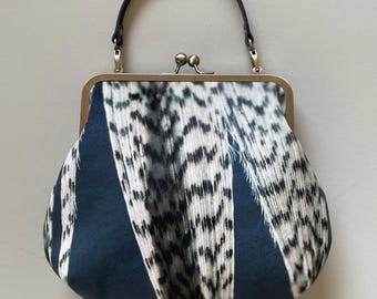 Borsa grande in velluto con chiusura a scatto e fantasia a righe di piume, con tracolla lunga o corta.