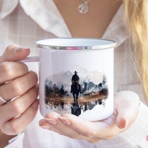 Woman holding a Cowboy enamel camping mug with a colorful Western design in her hands