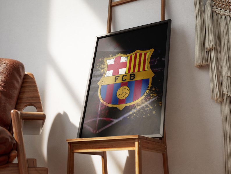 May include: A framed print of the FC Barcelona logo with a black background and yellow, red, and blue accents. The logo is surrounded by a splatter of white paint.