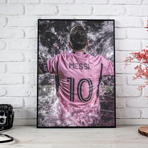 May include: A pink soccer jersey with the name "Messi" and the number "10" printed on the back. The jersey is worn by a player with a blurred background.