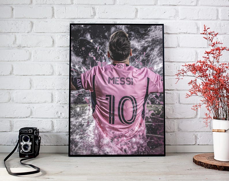 May include: A pink soccer jersey with the name "Messi" and the number "10" printed on the back. The jersey is worn by a player with a blurred background.
