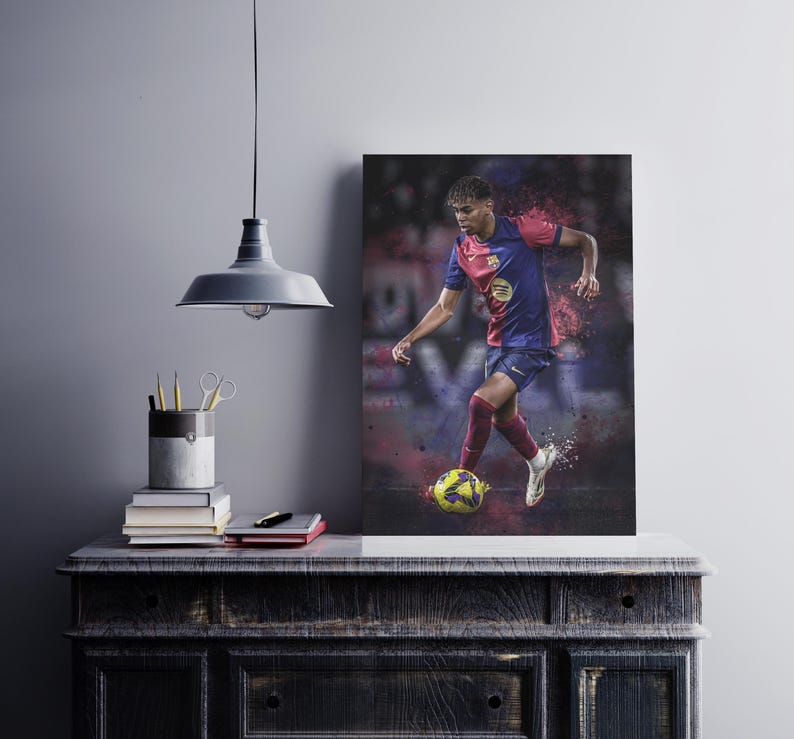 May include: A soccer player in a red and blue jersey with a yellow logo, dribbling a soccer ball. The player is wearing black shorts and white socks. The background is blurred and has a red and blue color scheme.