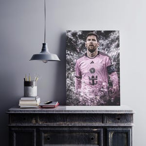 May include: A pink soccer jersey with black accents and a team logo. The jersey has a white trim around the collar and sleeves. The player is wearing the jersey and has a serious expression on his face.