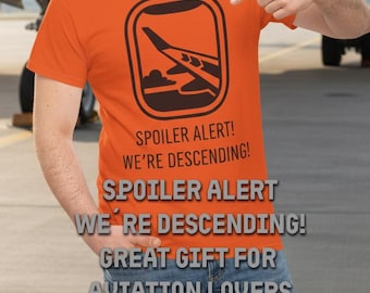 May include: Orange t-shirt with a black graphic of an airplane wing viewed from a window. The text "SPOILER ALERT! WE'RE DESCENDING!" is printed below the graphic. The shirt is a great gift for aviation lovers.