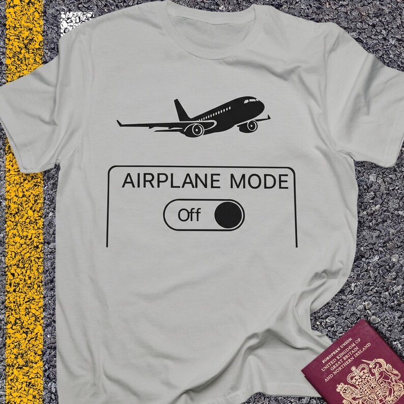 May include: A light gray t-shirt with a black graphic of an airplane and the words "AIRPLANE MODE" above a switch labeled "Off". The shirt is made of a soft material.
