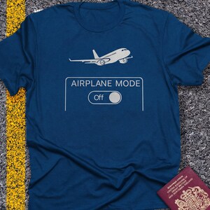 May include: A navy blue t-shirt with a white airplane graphic above the text "AIRPLANE MODE" and an "Off" switch. The design is simple and modern, perfect for travel enthusiasts.