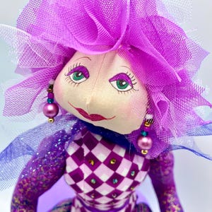 Handcrafted doll seated on a decorative storage box.