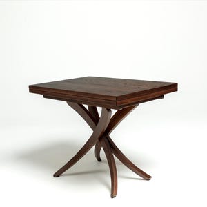 May include: A dark brown wooden table with a rectangular top and a unique, X-shaped base. The table is made of solid wood and has a natural finish.