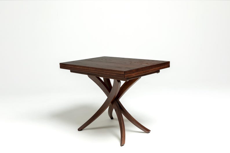 May include: A dark brown wooden table with a rectangular top and a unique, X-shaped base. The table is made of solid wood and has a natural finish.