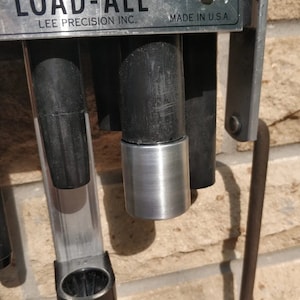 Könnte beinhalten: Nahaufnahme einer silbernen Metall-Ladematrize mit einem schwarzen Kunststoffgriff. Die Matrize ist mit "LOAD-ALL" und "LEE PRECISION INC." beschriftet.