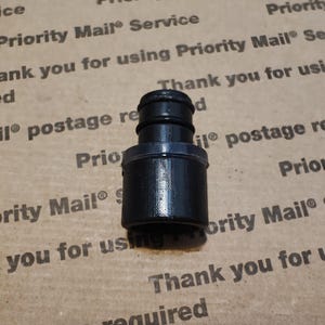 Pode incluir: Conector de plástico preto com duas aberturas. O conector é projetado para conectar duas mangueiras ou tubos.