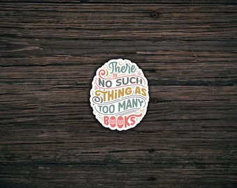 May include: A sticker with a white background and colorful text that reads "There is no such thing as too many books". The sticker is on a dark brown wooden surface.