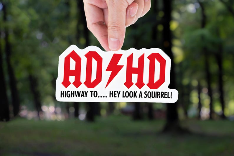 Funny ADHD sticker with bold red and black text that says “ADHD Highway to… Hey look a squirrel!” in a rock-band inspired design.