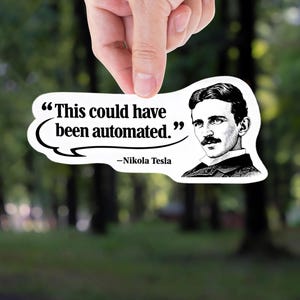 May include: A white sticker with a quote by Nikola Tesla, held by a hand against a blurred green background. The sticker features a speech bubble with the text "This could have been automated." and a portrait of Tesla.