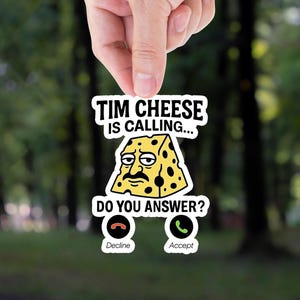 May include: A white sticker with a cartoon wedge of cheese with a face and the text "Tim Cheese is calling... Do you answer?" with two phone icons below, one labeled "Decline" and the other labeled "Accept".