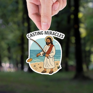 May include: A sticker featuring an illustration of Jesus fishing with the text "CASTING MIRACLES". Jesus is depicted on a beach with a fishing rod, a loaf of bread, and the ocean in the background.