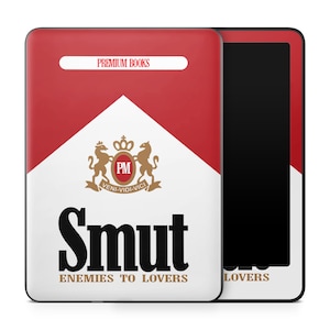 May include: A red, white, and black e-reader case with the word "Smut" in large black letters. The case has the text "Premium Books" and "Enemies to Lovers" printed on it. A black e-reader is visible.