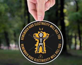 May include: A round sticker with a black background and white border. The sticker features a yellow skeleton with lightning bolts and the text "REMEMBER KIDS ELECTRICITY WILL KILL YOU" in a circular pattern.