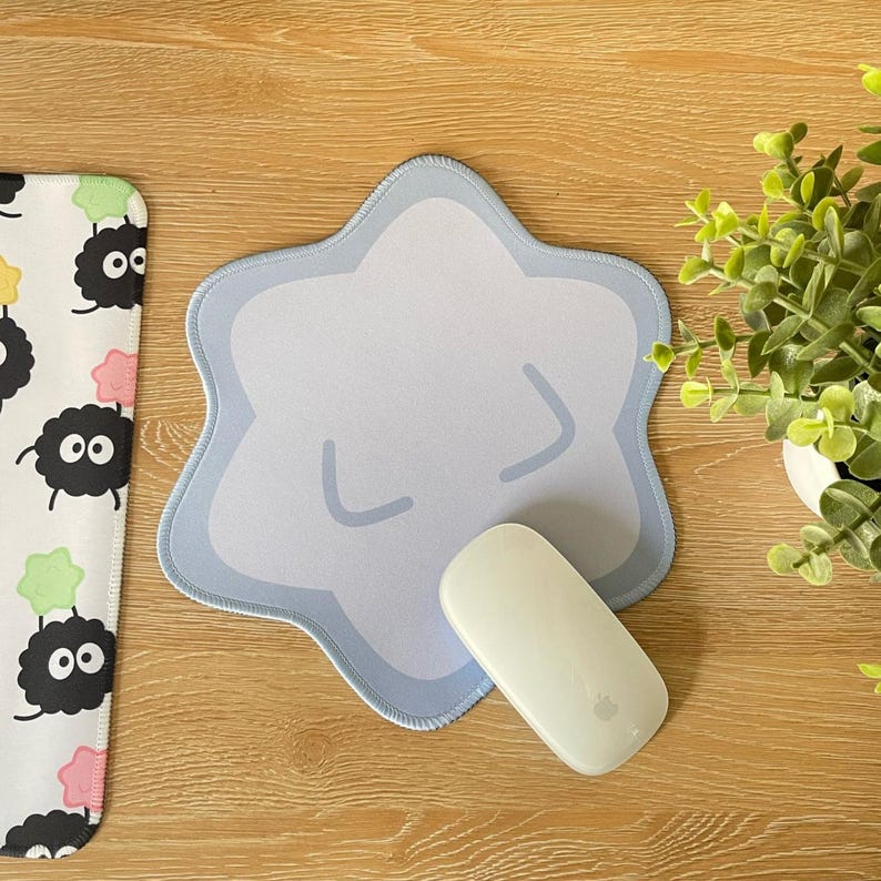 May include: A light blue star-shaped mousepad with a cartoon face and a white wireless mouse on top.