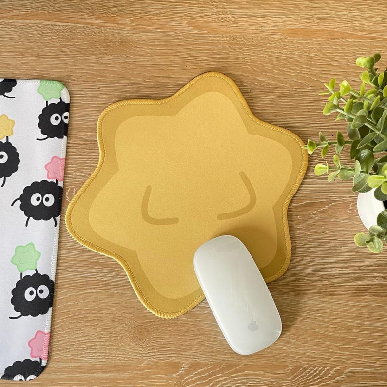 May include: A yellow star-shaped mousepad with a white computer mouse on top. The mousepad has a slightly raised edge.