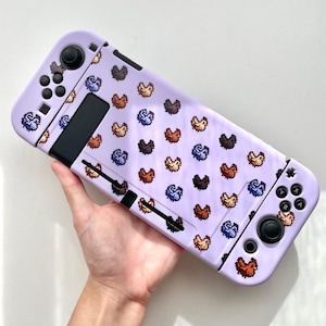 May include: A lilac Nintendo Switch case with a repeating pattern of pixelated chickens in various colours. The case has black buttons and joystick controls. The Switch case is designed to protect the console.