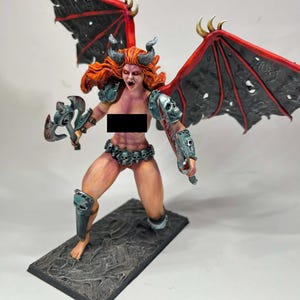 May include: A detailed figurine of a female demon warrior with red hair, horns, and large black and red wings. She is holding a double-bladed axe and a sword, wearing skull-adorned armor and a belt. The figurine is mounted on a textured rectangular base.