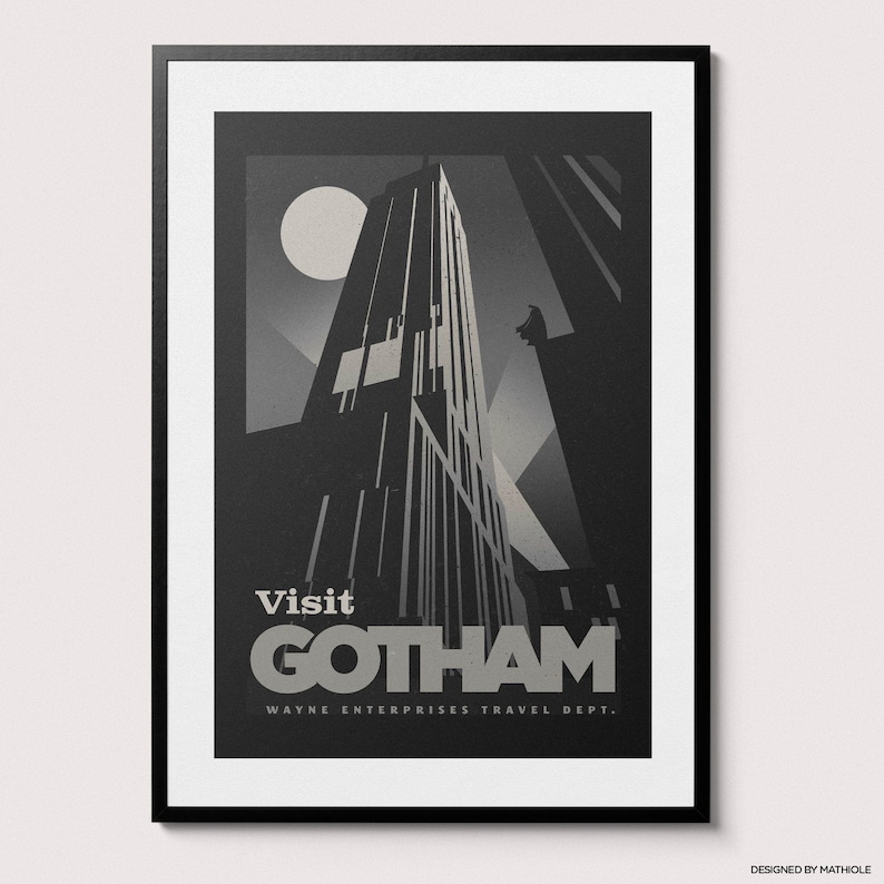 May include: Framed art print featuring a stylized, grayscale depiction of a skyscraper under a full moon. The poster reads "Visit Gotham" with "Wayne Enterprises Travel Dept." below. A dark silhouette of a figure is perched on a building.