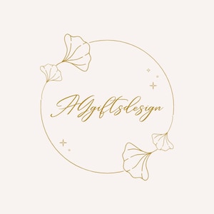 Peut inclure: Un logo en art linéaire de couleur dorée sur fond clair, composé d'un cadre circulaire orné de feuilles de ginkgo et de petites étoiles. Le texte AGgiftsdesign est écrit en écriture cursive au centre du cercle.