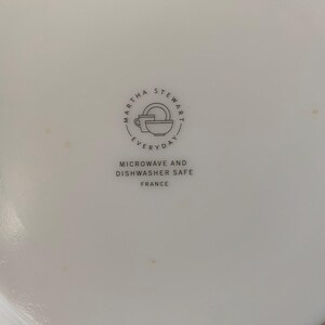 May include: White ceramic plate with the Martha Stewart Everyday logo, featuring a cup, bowl, and plate. Text below reads "Microwave and Dishwasher Safe" and "France."