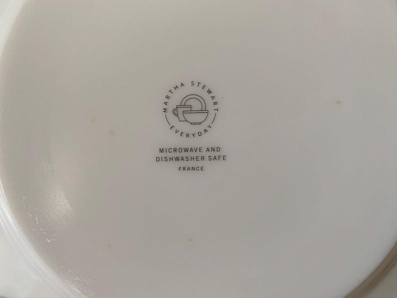May include: White ceramic plate with the Martha Stewart Everyday logo, featuring a cup, bowl, and plate. Text below reads "Microwave and Dishwasher Safe" and "France."
