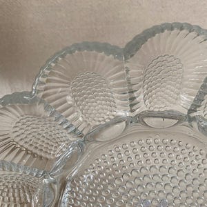May include: A clear glass serving dish with a scalloped edge and a textured design. The dish is divided into sections, each with a different pattern.