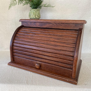 May include: A white ceramic mug with a black handle and the text "But First, Coffee" in a bold, black font. The mug is set against a blurred background, suggesting a cozy setting. The mug appears to be approximately 4 inches tall.