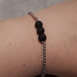 May include: A silver chain bracelet with three black lava rock beads.